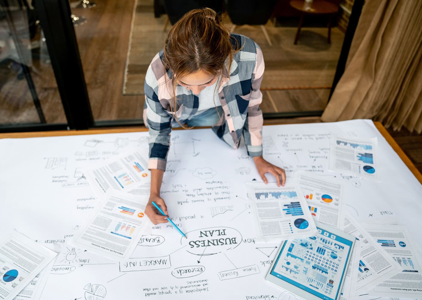 een vrouw werkt aan haar businessplan. We hebben een aantal tips voor het schrijven van een boeiende zakelijke beschrijving.